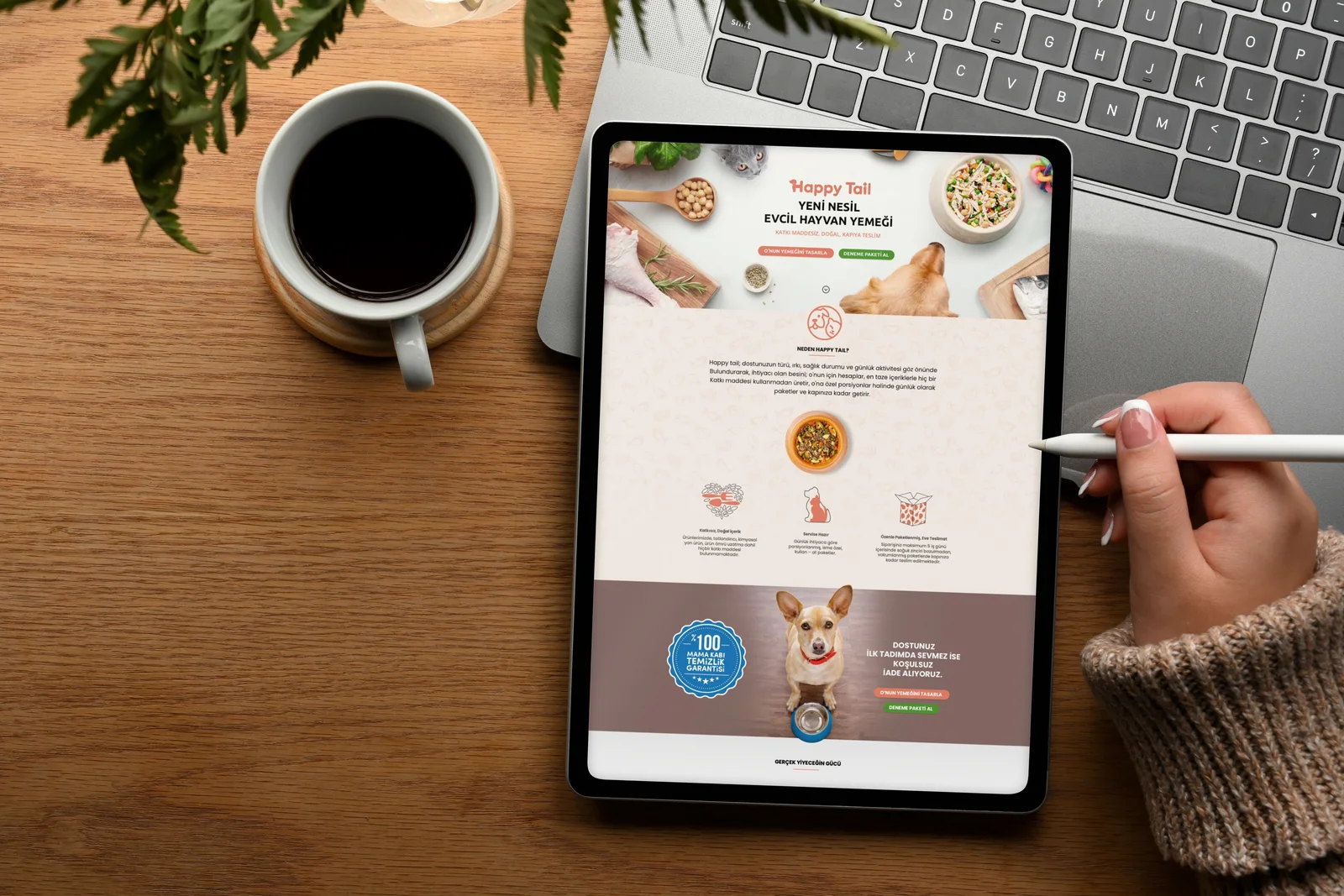 Ahşap masada ekranında Happy Tail web sitesi açık tablet, ekrana kalemle dokunan el ve yanında kahve fincanı